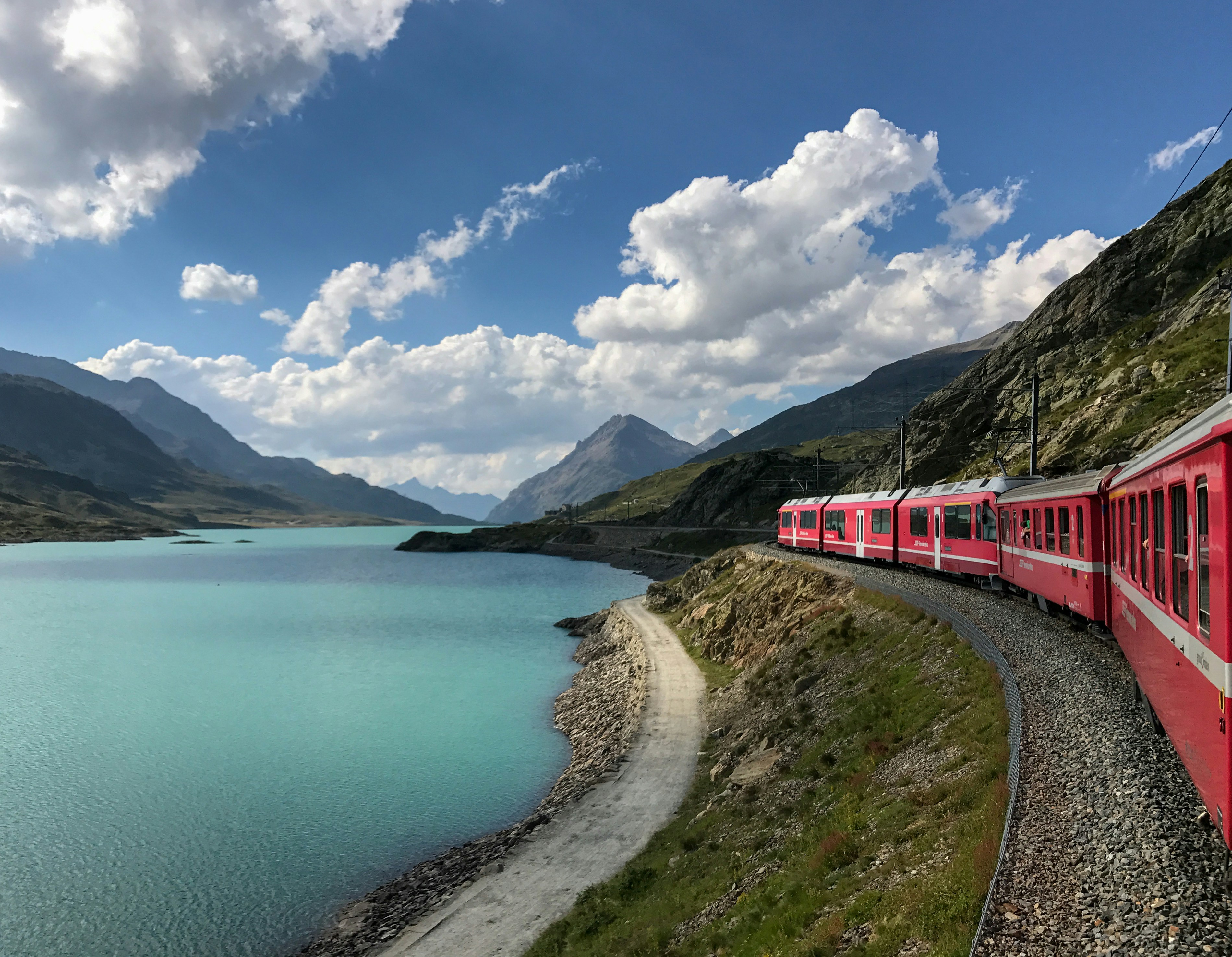 Red Swiss train winding along turquoise mountain lake